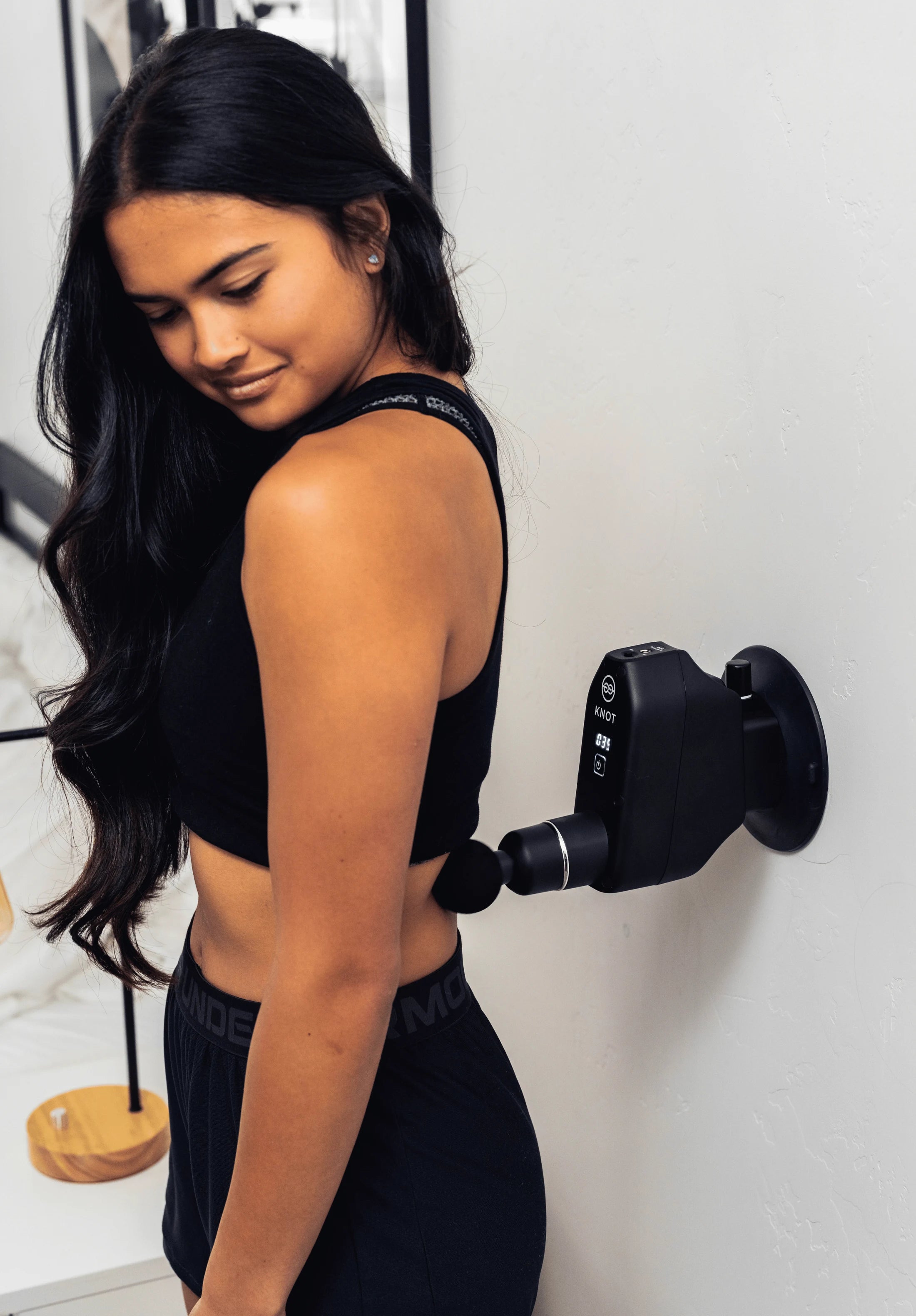 Wall-mounted massage gun used with bodyweight